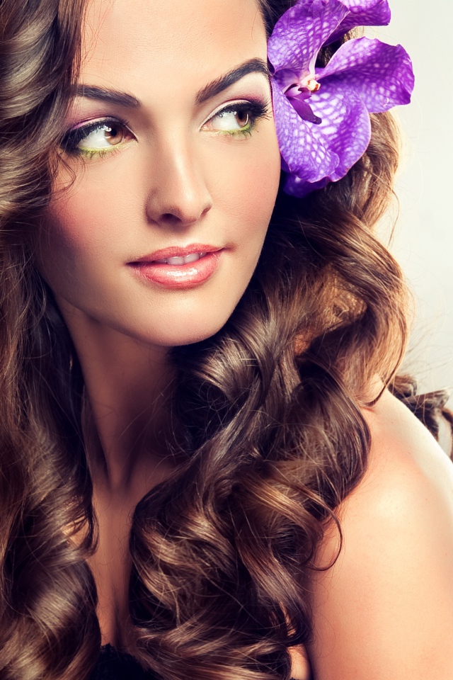 Цветок в красивых длинных волосах молодой девушки