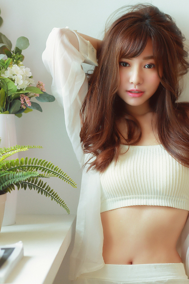 Нежная девушка азиатка стоит у окна