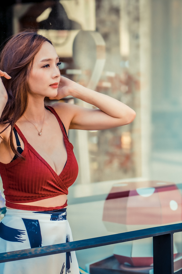 Нежная девушка азиатка стоит на балконе 