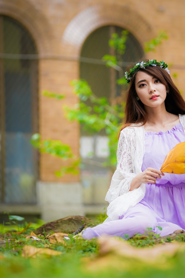 Девушка в красивом платье сидит на траве 