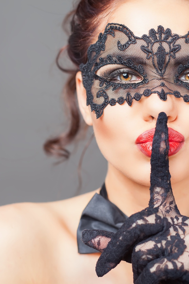 Девушка в черной маске с рукой в перчатке у лица