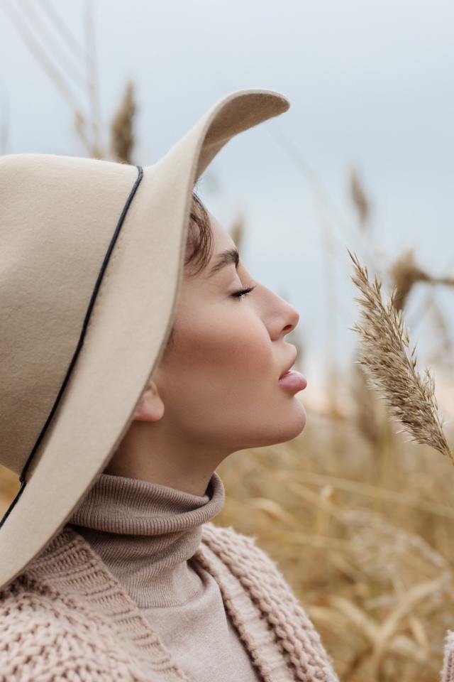 Девушка в шляпе с закрытыми глазами держит колосок 