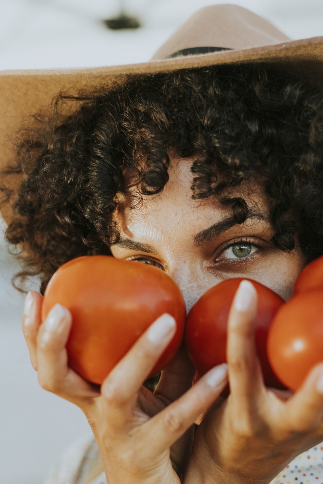 Девушка в шляпе с помидорами в руках 