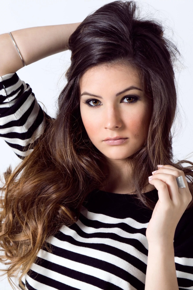 Девушка в полосатом свитере с рукой в волосах на белом фоне