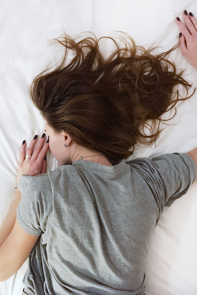 Девушка в серой пижаме спит на кровати 