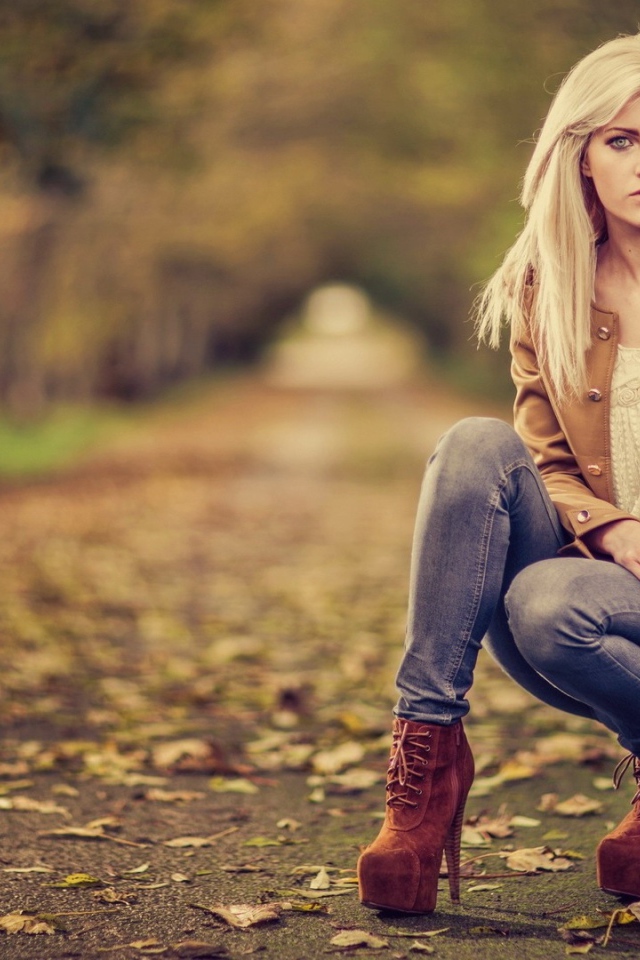 Девушка на высоких каблуках сидит на корточках в парке