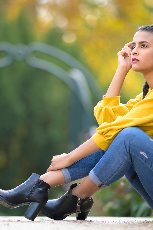 Девушка в джинсах сидит на земле 