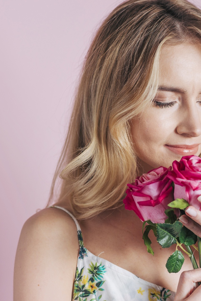Девушка вдыхает аромат роз  