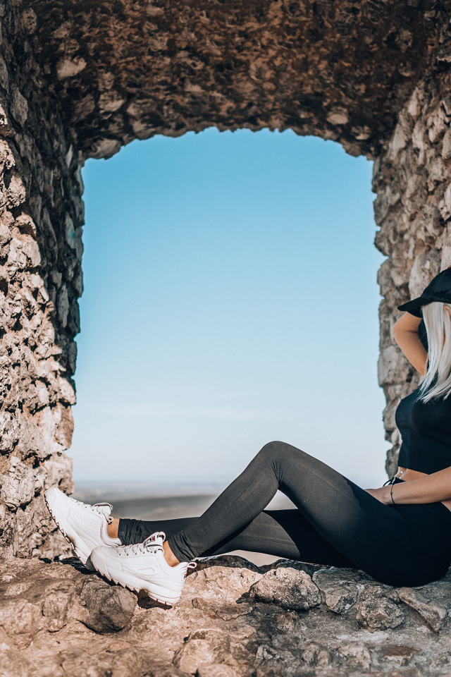 Девушка сидит в окне старого здания 