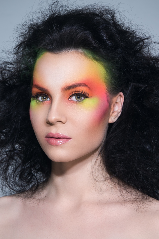 Девушка с начесом на волосах с ярким макияжем на сером фоне