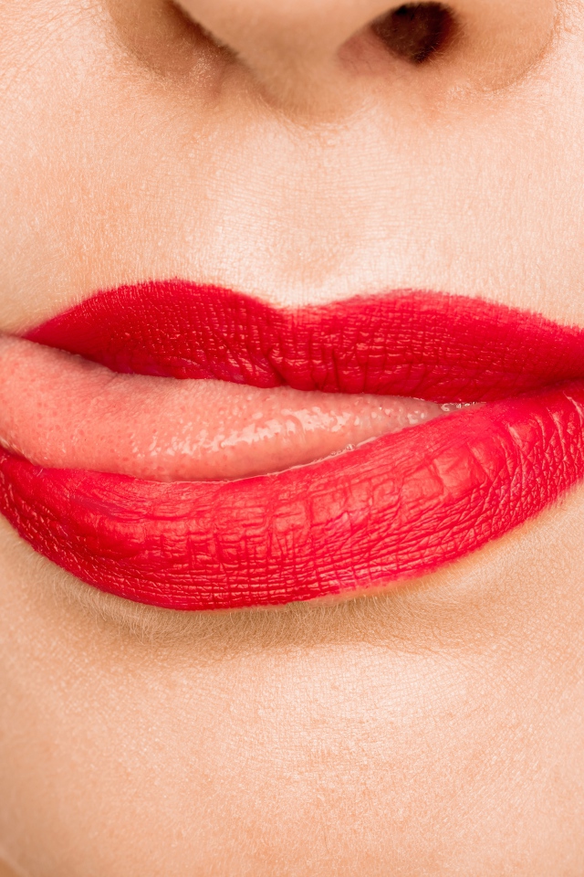 Девушка с  красными губами показывает язык