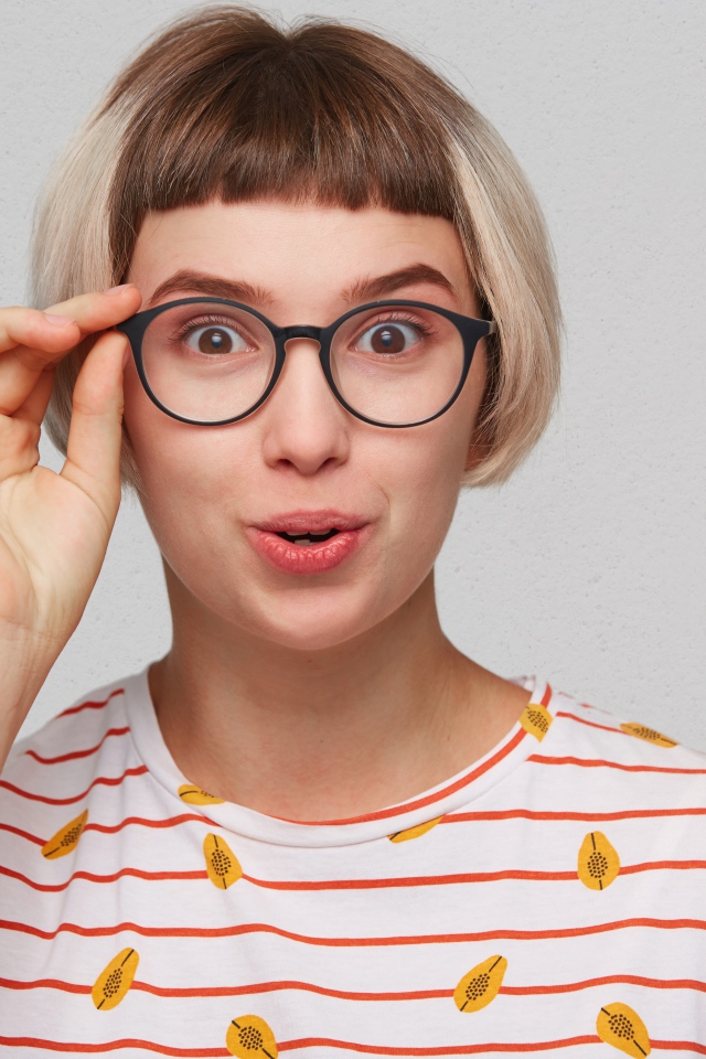 Девушка с короткой стрижкой поправляет очки 