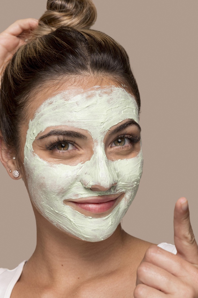 Девушка с завязанными волосами с косметической маской на лице