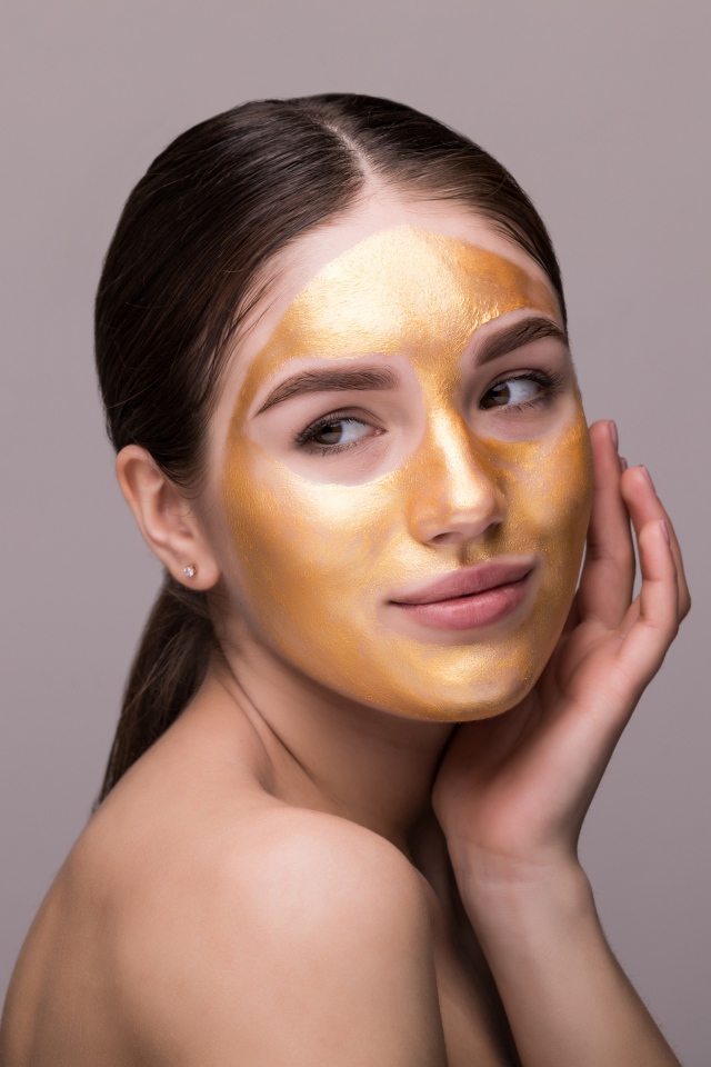 Золотая маска на лице у молодой девушки 