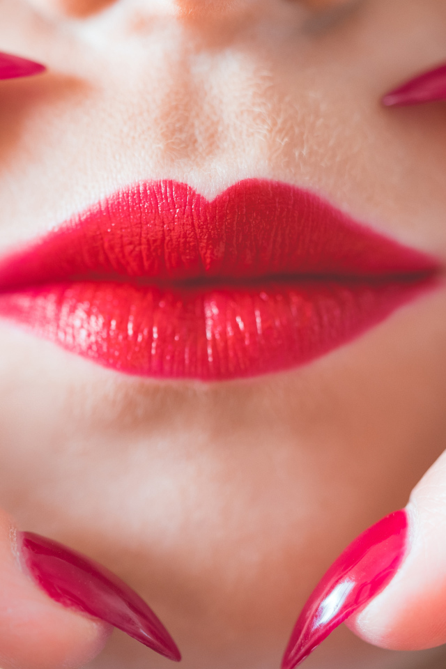 Руки с длинными красными ногтями у губ