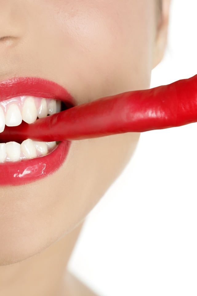 Hot pepper in a girl’s mouth with beautiful white teeth