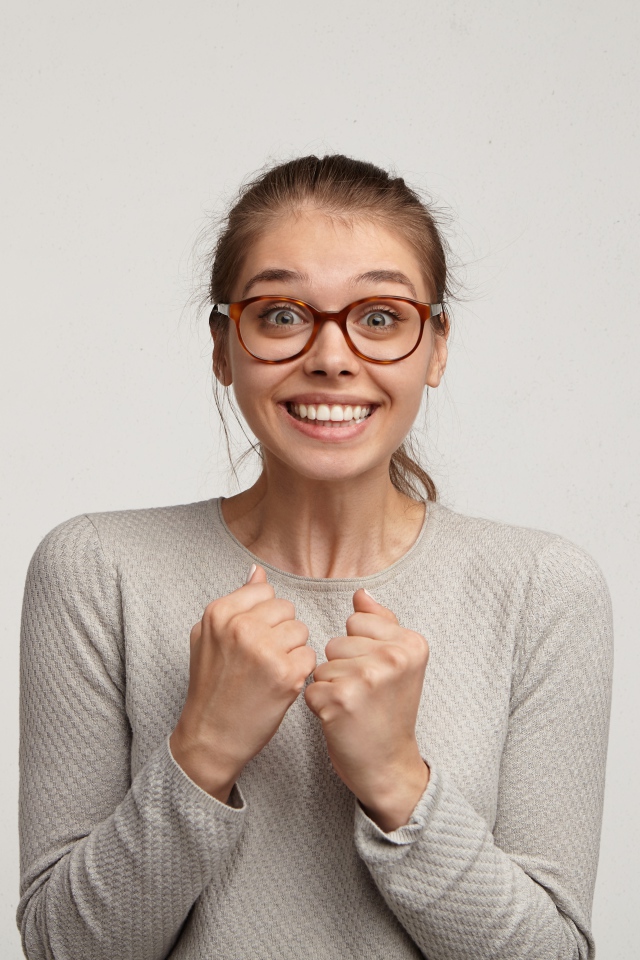 Радостная девушка в очках для зрения на сером фоне 