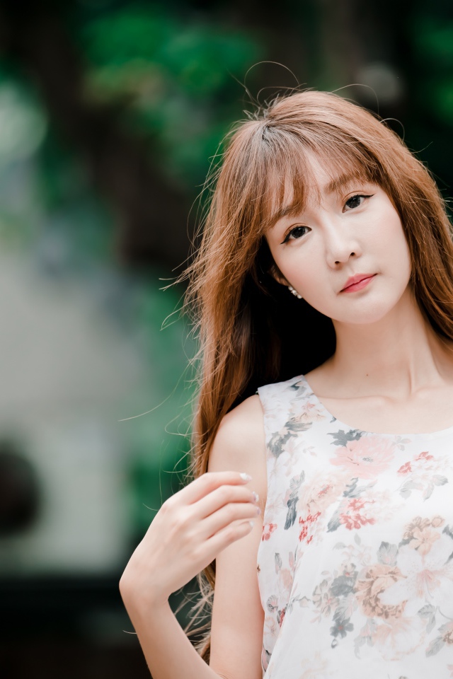 Длинноволосая азиатка стоит у стены 