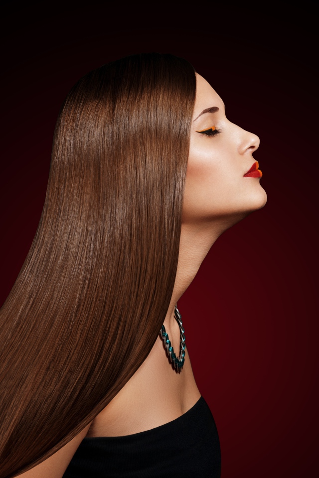 Длинноволосая шатенка с закрытыми глазами на красном фоне