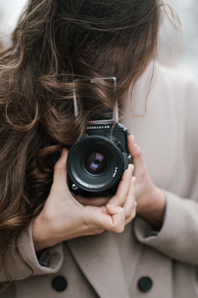 Длинноволосая девушка с фотоаппаратом в руках 