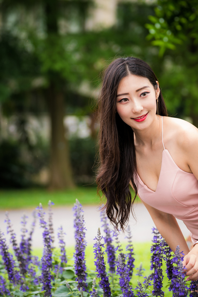 Милая девушка Азиатка в розовом платье у синих цветов