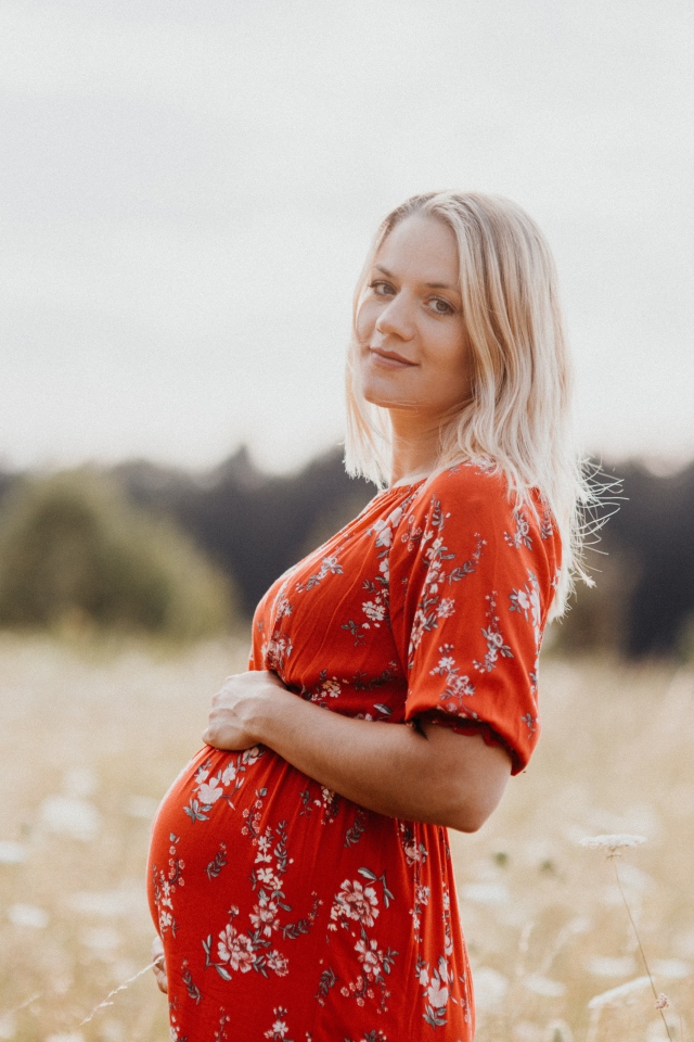 Беременная девушка в красном платье на поле