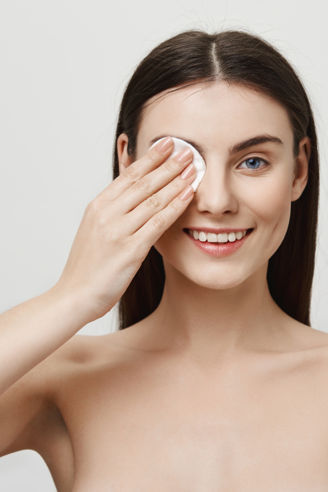 Настоящая голубоглазая девушка снимает макияж с лица