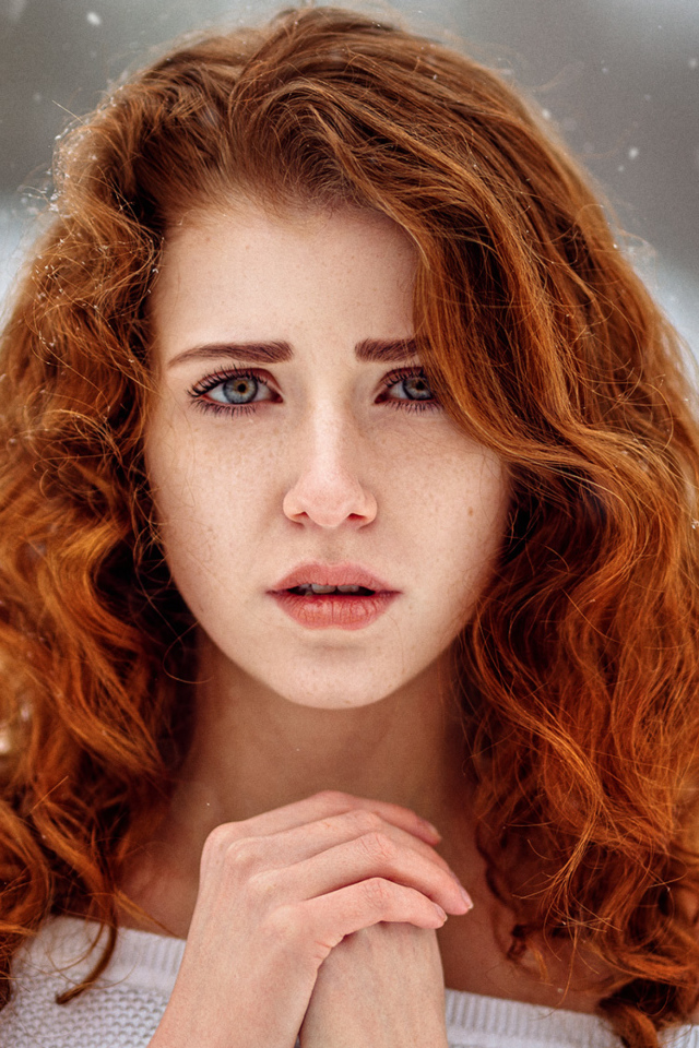 Рыжеволосая девушка замерзает на улице зимой