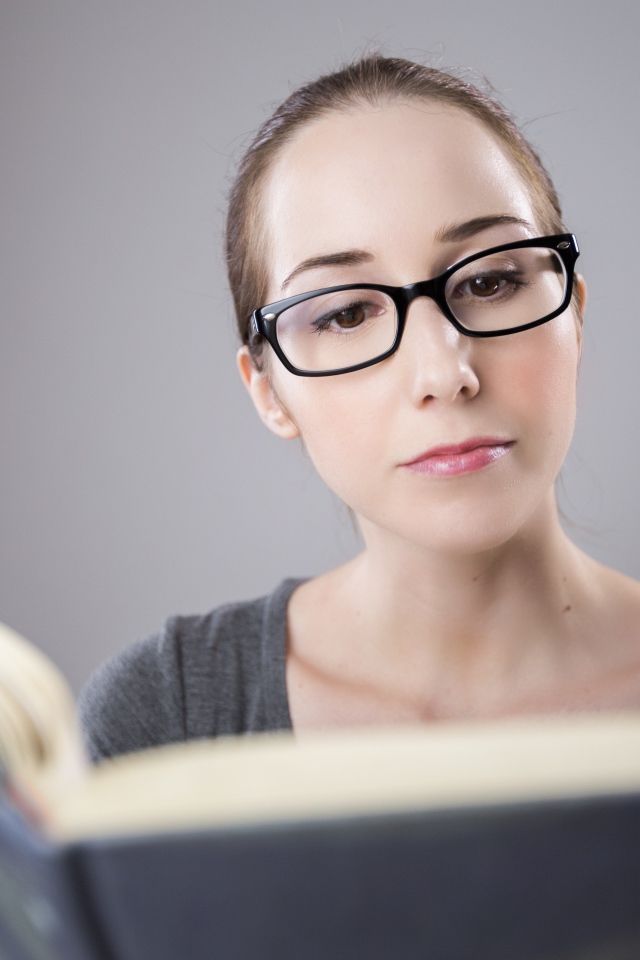 Умная девушка в очках читает книгу 