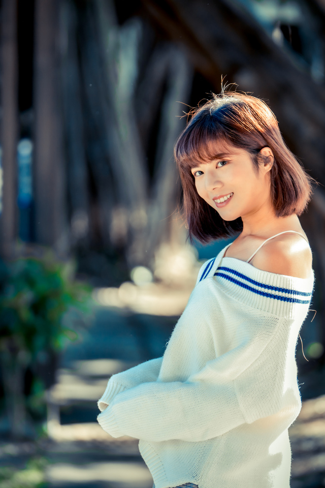 Улыбающаяся девушка азиатка в белом свитере 