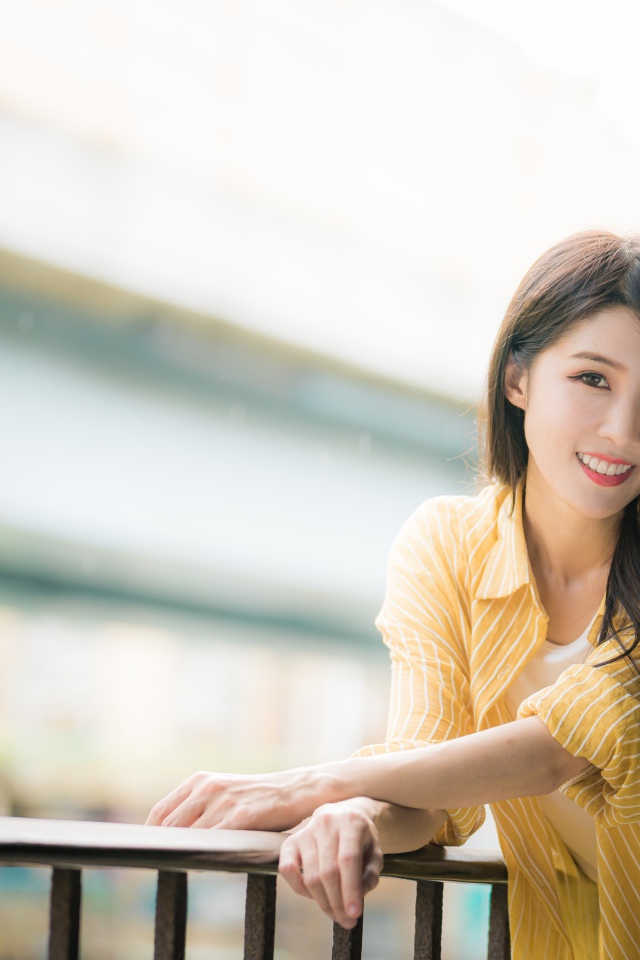 Улыбающаяся азиатка в желтой полосатой рубашке