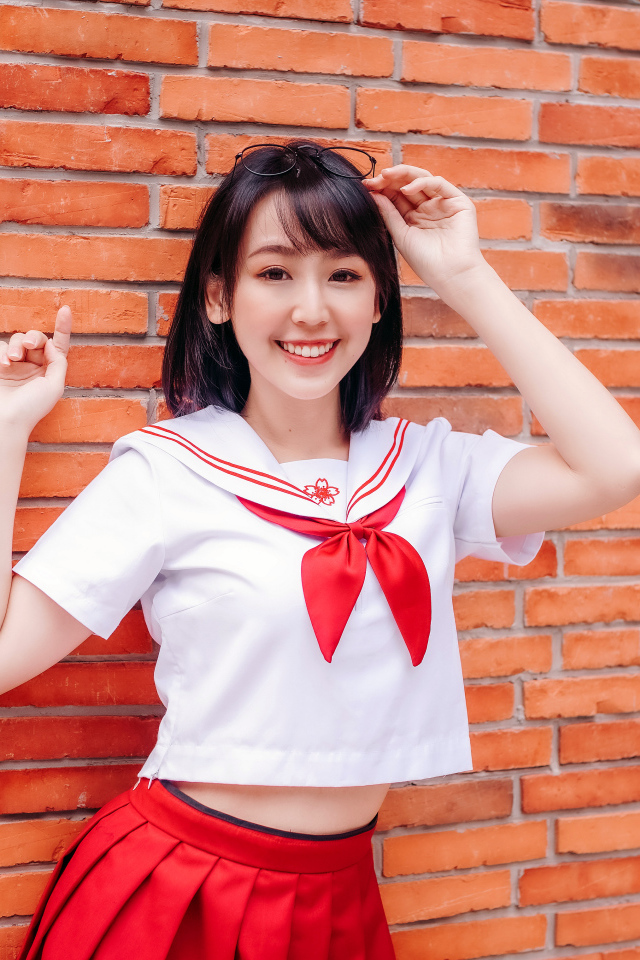 Улыбающаяся азиатка стоит у стены 