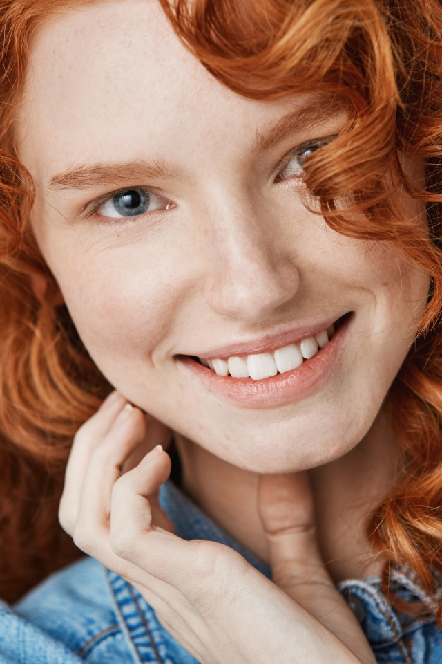 Улыбающаяся голубоглазая рыжеволосая девушка в джинсовой куртке 