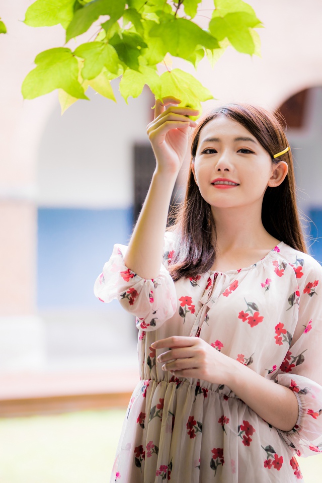 Улыбающаяся девушка в платье у дерева 