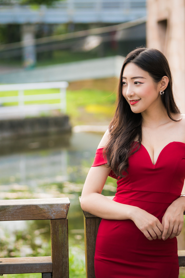 Улыбающаяся девушка в красном платье у перил 