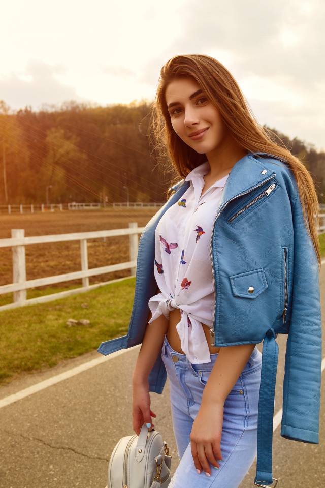 Улыбающаяся девушка в синей кожаной куртке на дороге 