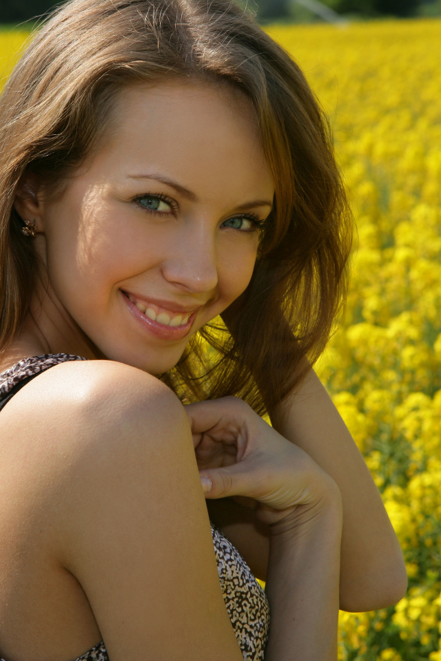Улыбающаяся девушка на фоне поля с желтыми цветами