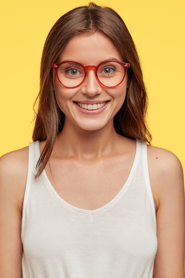 Улыбающаяся девушка в очках на желтом фоне 