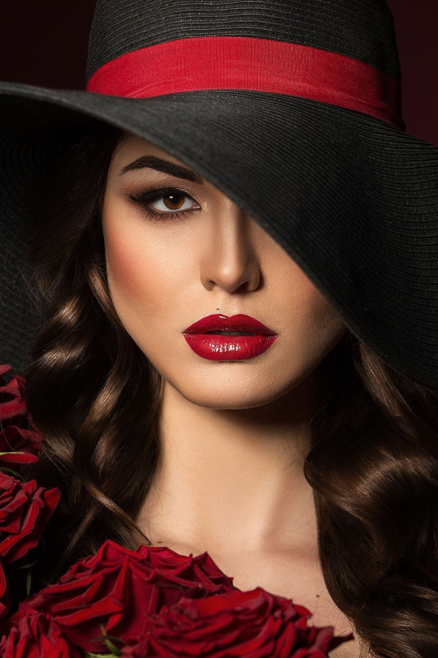 Эффектная девушка в большой черной шляпе с букетом роз