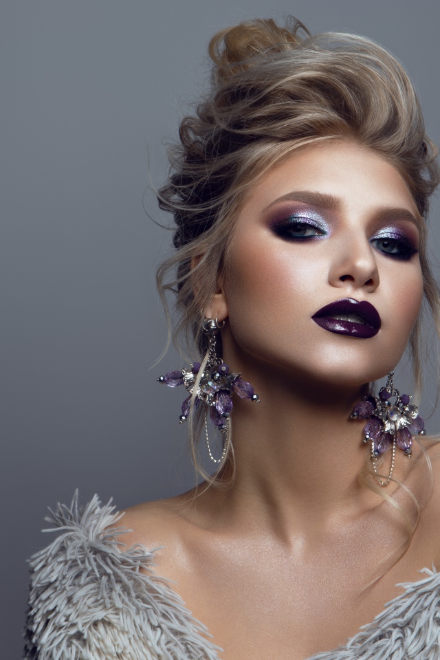 Эффектная девушка с ярким макияжем на сером фоне