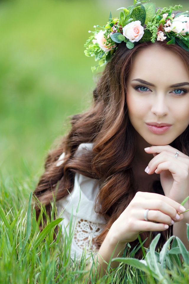 Эффектная настоящая девушка с венком на голове лежит на траве