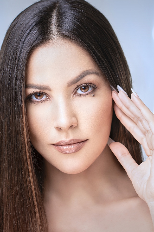 Стильная кареглазая длинноволосая брюнетка с рукой у лица