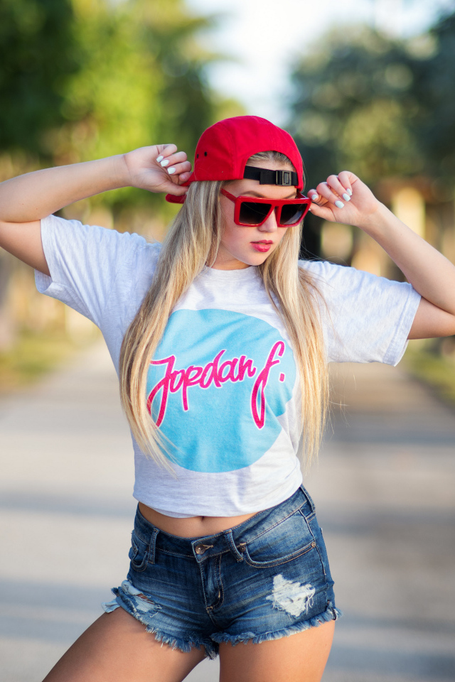 Стильная девушка в красной кепке и джинсовых шортах 