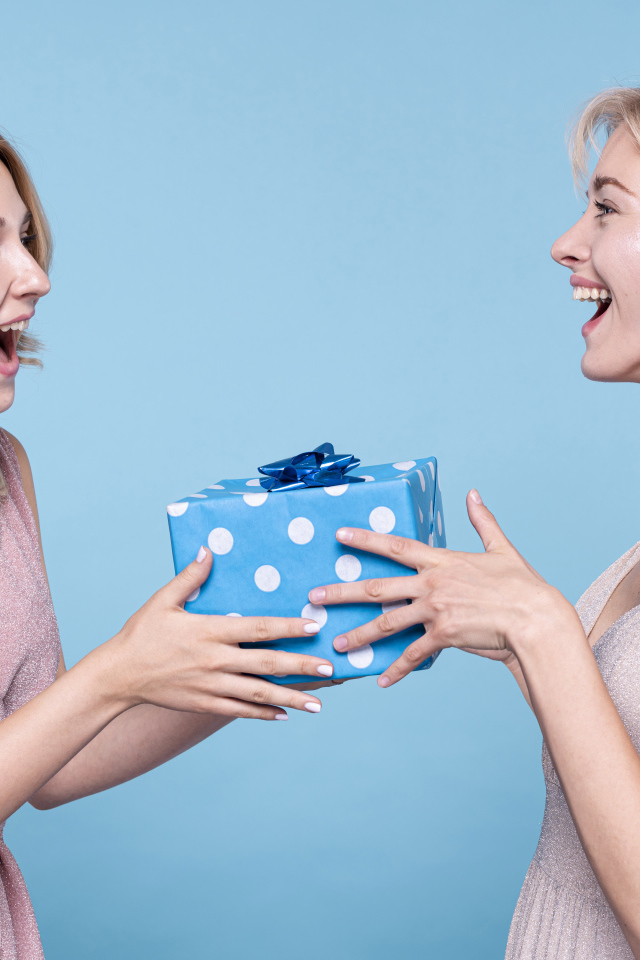 Две веселые подруги с подарком на голубом фоне