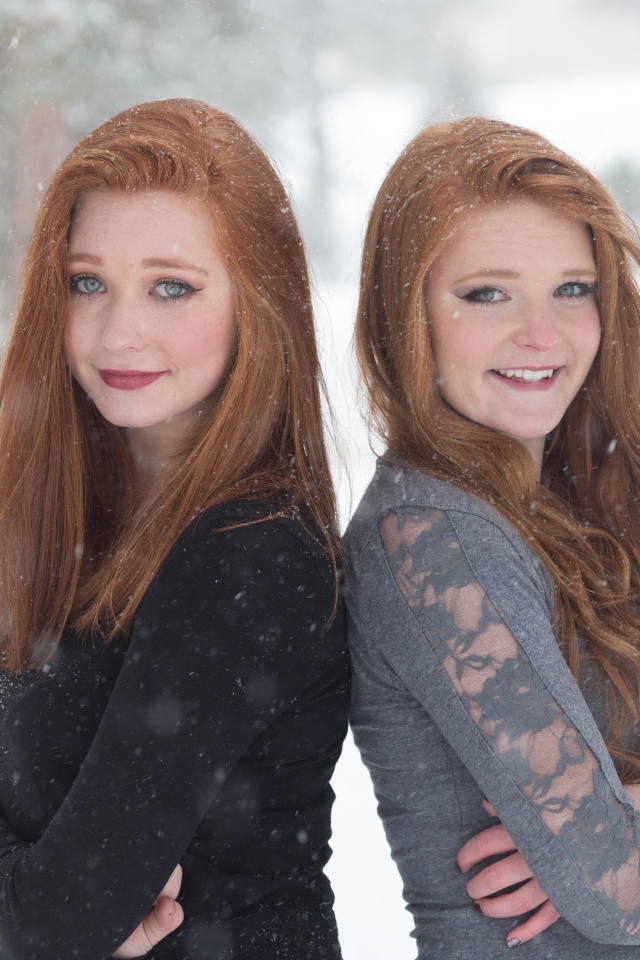 Две улыбающиеся рыжеволосые сестры на улице зимой 