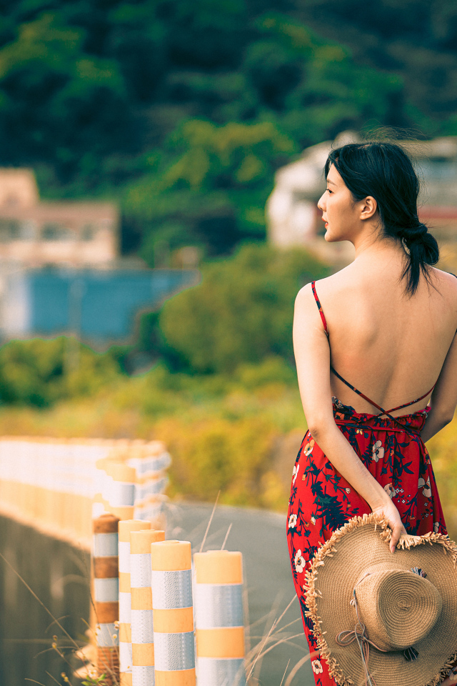 Молодая девушка азиатка в сарафане со шляпой в руке 