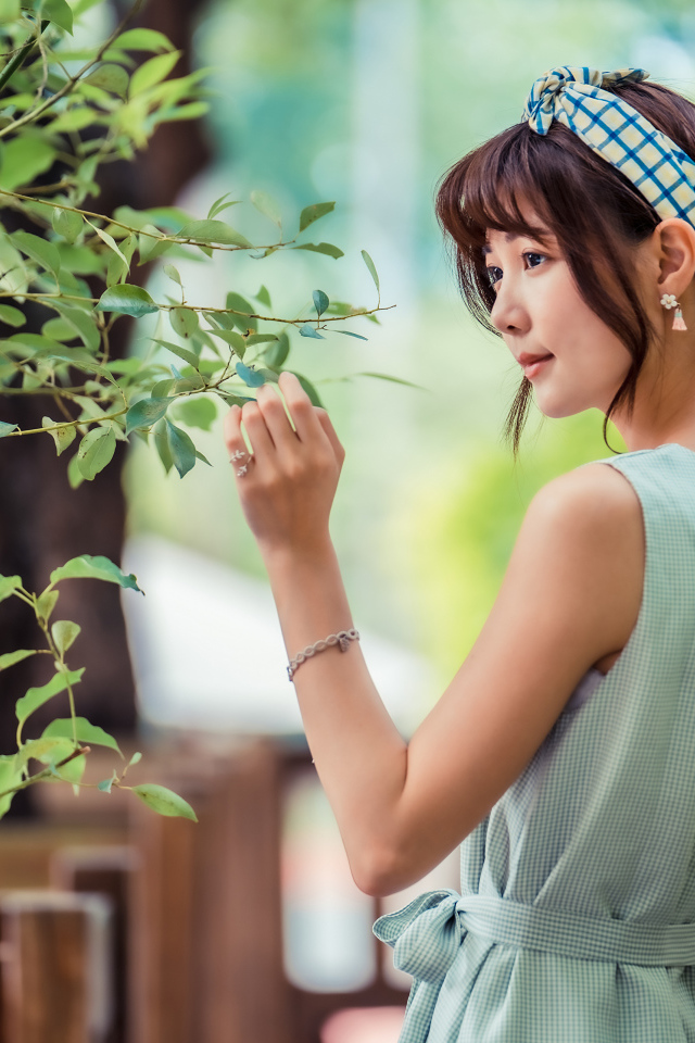 Молодая девушка азиатка с повязкой на голове у дерева 