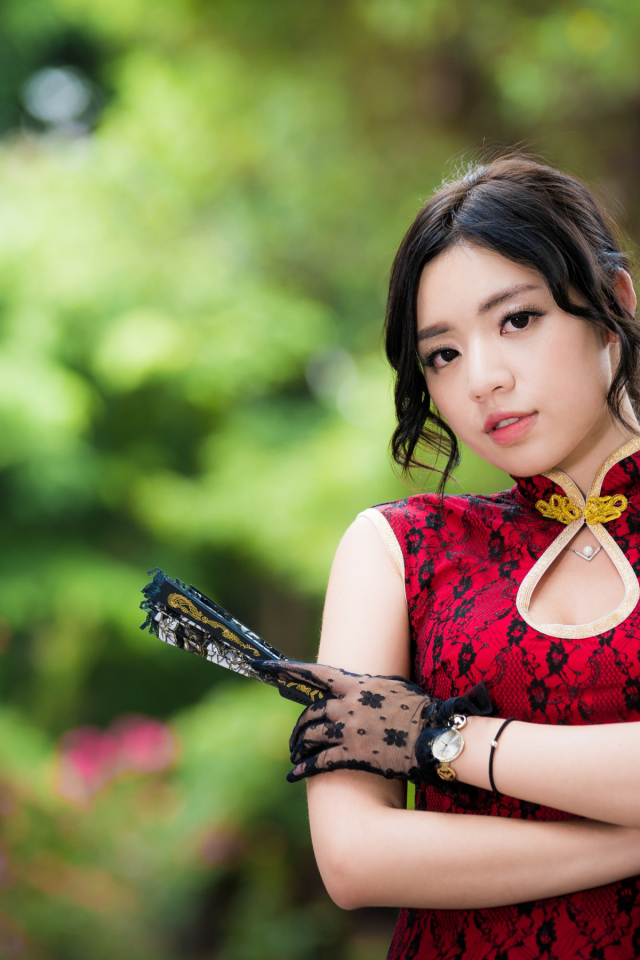 Молодая азиатка в красивом платье с веером в руке