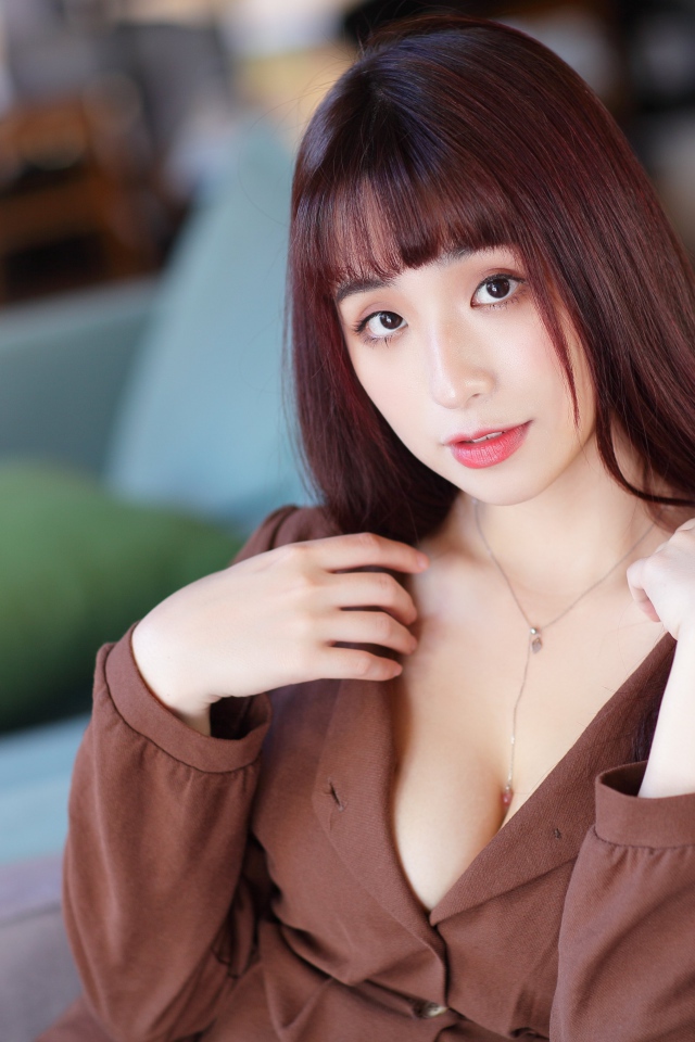 Молодая азиатка сидит на диване 