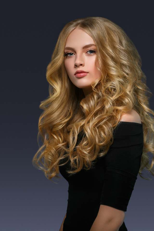 Молодая блондинка с красивыми длинными волосами в черном платье